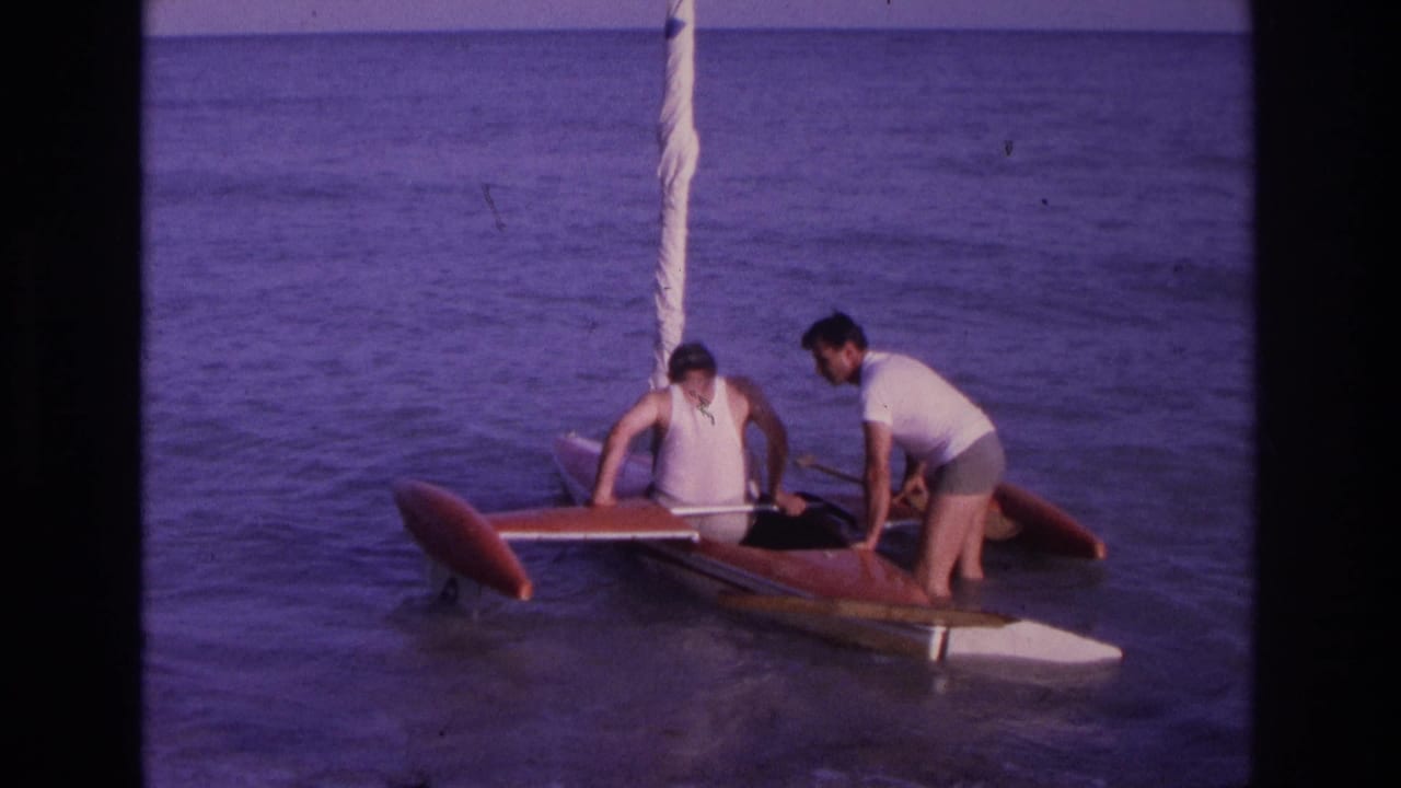 One man sits in the boat while another leans over the stern area.