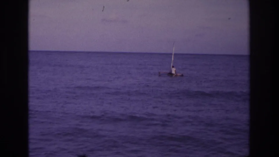 Distant 1968 Ocean City coastal view of a person on a small sail raft against a flat ocean horizon.