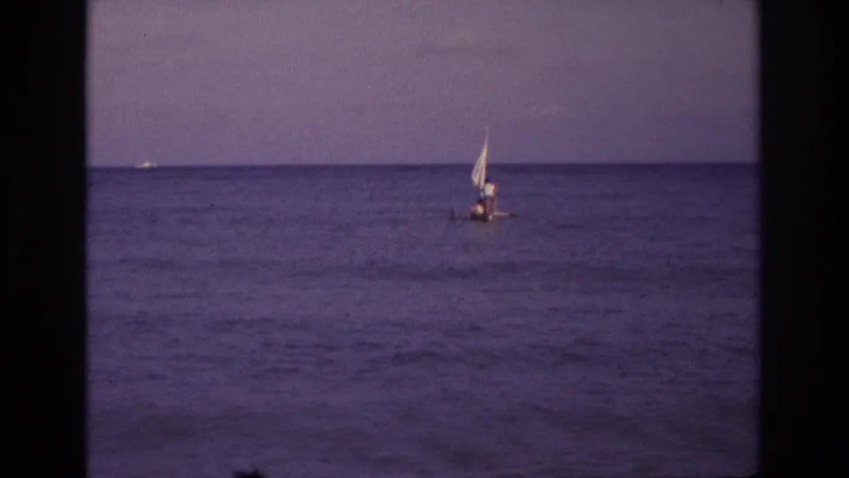 A wider 1968 Ocean City ocean view with the small sailboat farther right in frame, sail raised and occupants barely discernible.