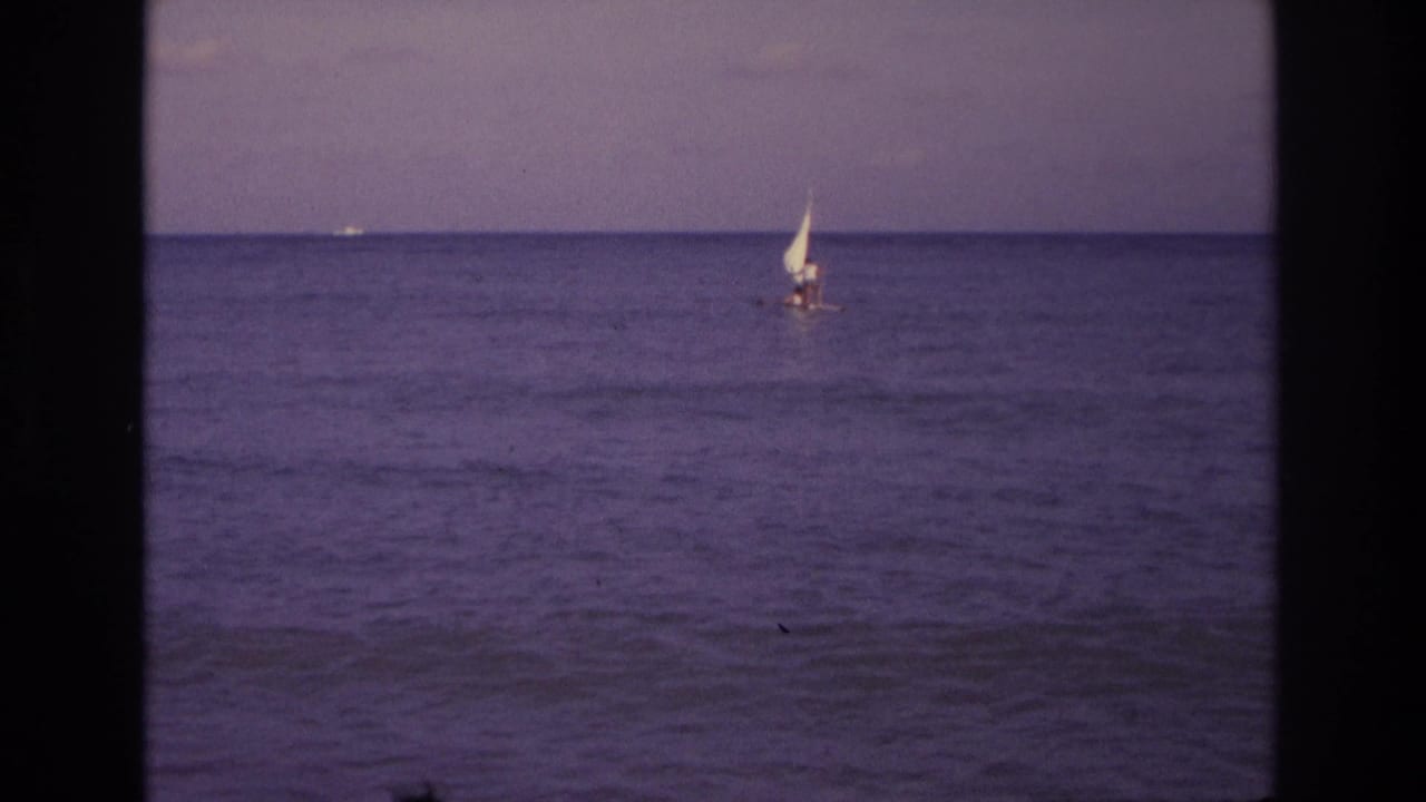1968 Ocean City, New Jersey 8mm frame showing a small sailboat offshore with a calm ocean horizon and purple film cast.