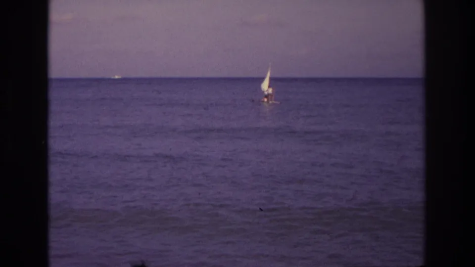 1968 Ocean City, New Jersey 8mm frame showing a small sailboat offshore with a calm ocean horizon and purple film cast.