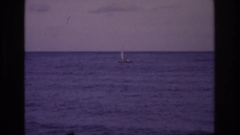 Distant sailboat on the Ocean City shoreline view, with soft 8mm grain, purple color shift, and a dark central frame edge.