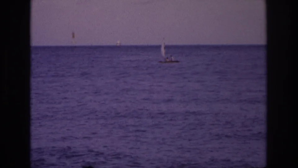 Ocean City, New Jersey 1968 8mm frame with a small sailboat offshore, muted sky, grain, and strong purple color cast.