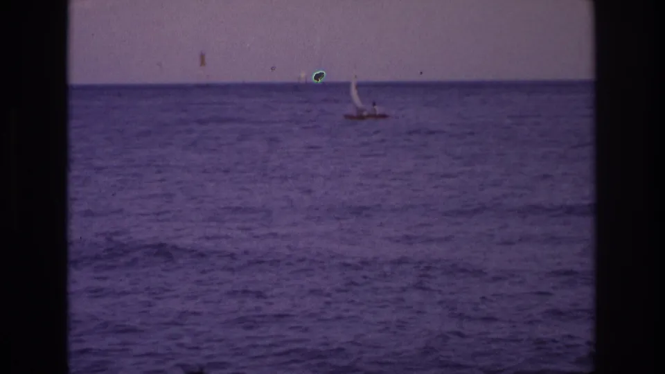 1968 Ocean City, New Jersey 8mm frame showing the sailboat farther right, with hazy horizon detail and visible film specks.