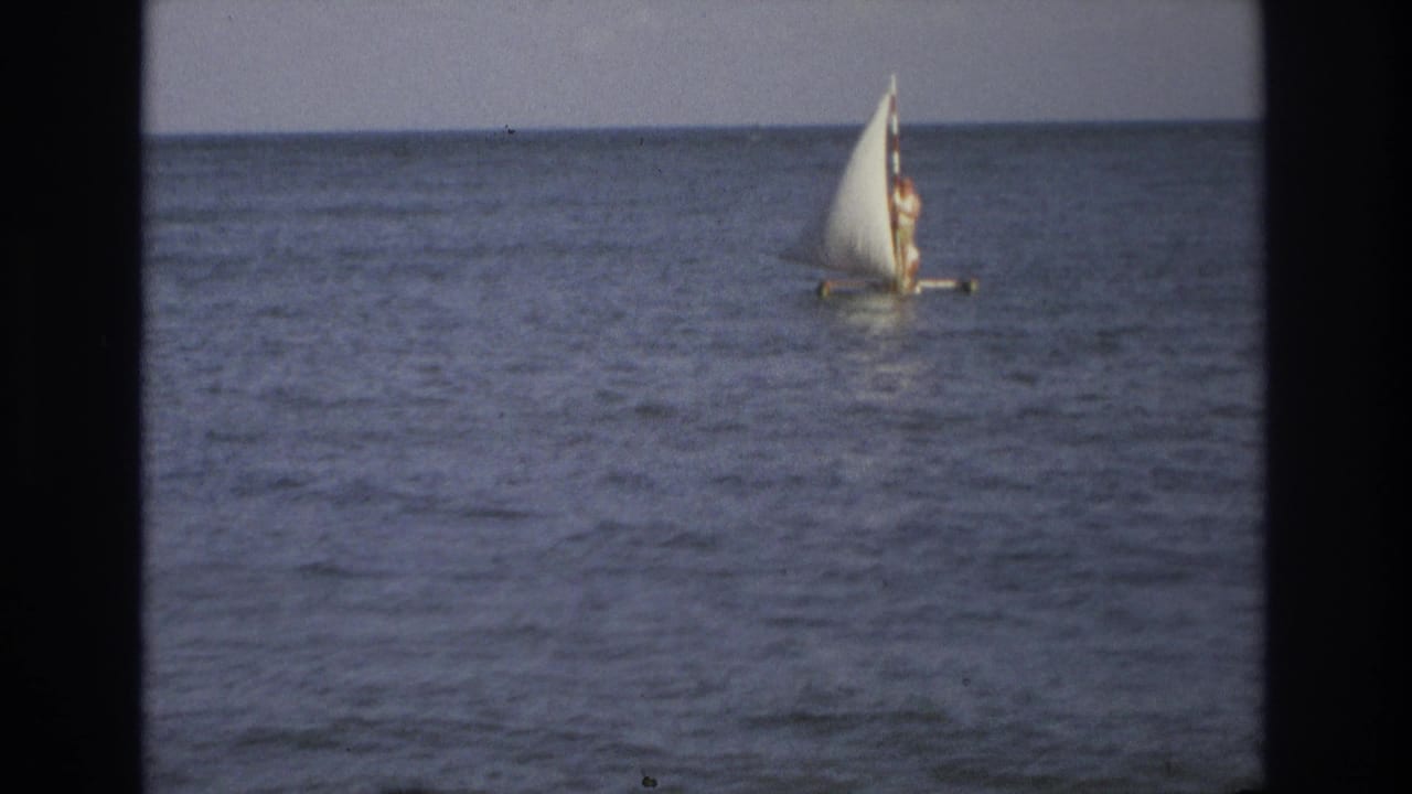 1968 Ocean City, New Jersey 8mm frame showing a distant person standing on a small sailboat with a full white sail.