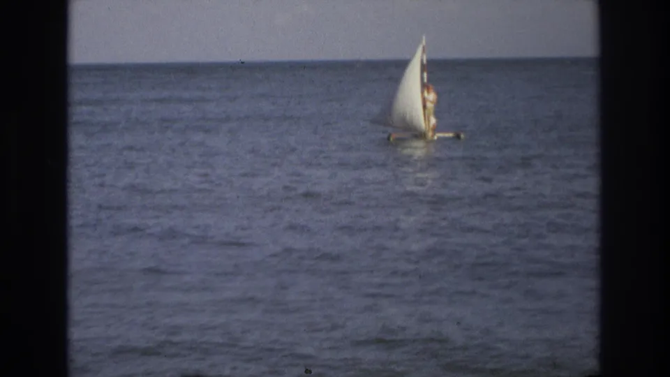 1968 Ocean City, New Jersey 8mm frame showing a distant person standing on a small sailboat with a full white sail.