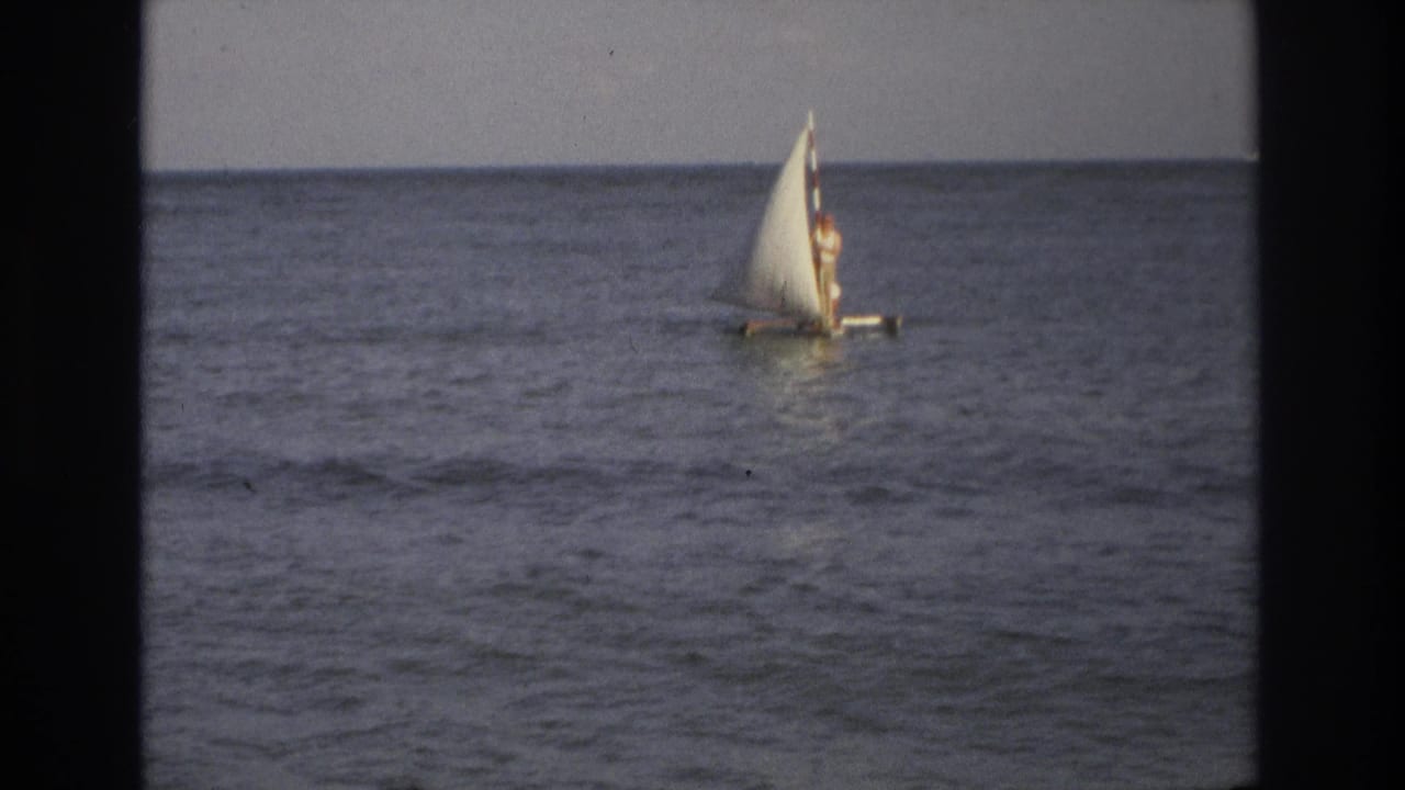 1968 Ocean City, New Jersey 8mm frame showing a small white sailboat with a distant rider bobbing on open water.