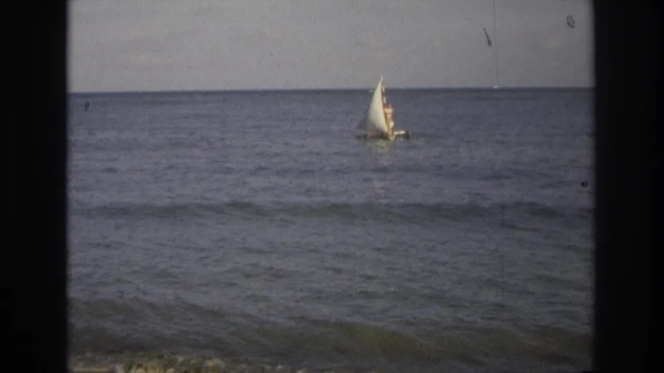1968 Ocean City, New Jersey frame of a small sailboat receding across the ocean under a subdued sky.