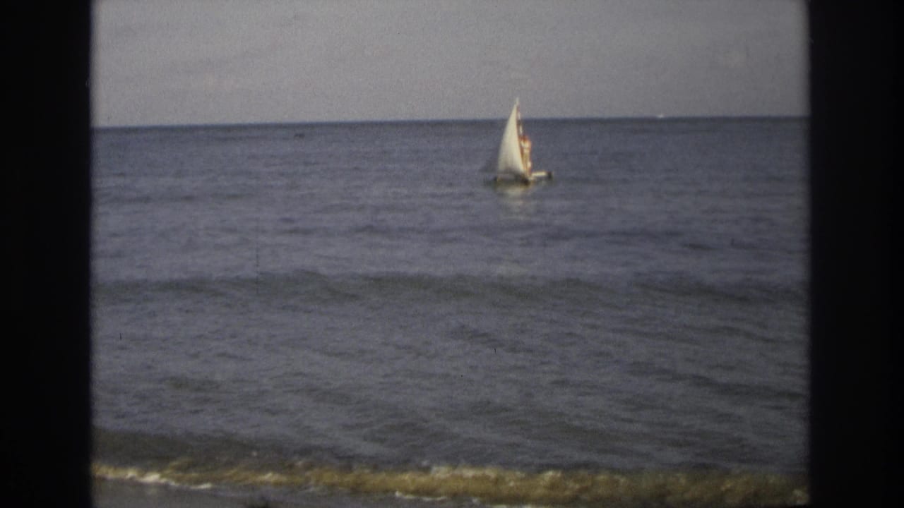 1968 Ocean City, New Jersey 8mm frame showing a small white sailboat offshore on calm water under a muted sky.