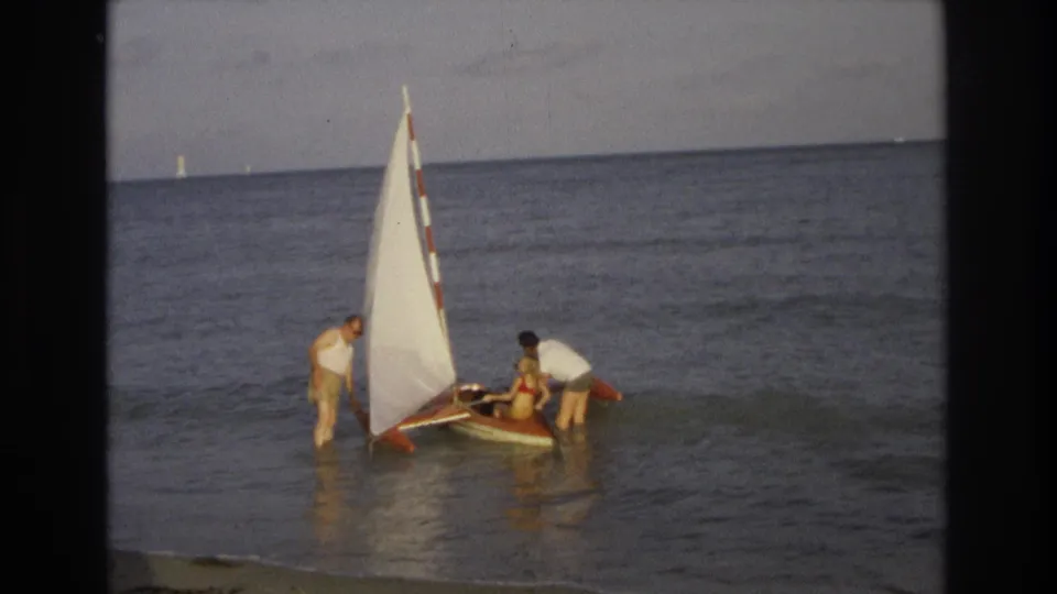 The group continues guiding the small sailboat through gentle surf in Ocean City, New Jersey, consistent with the 1968 clip metadata.