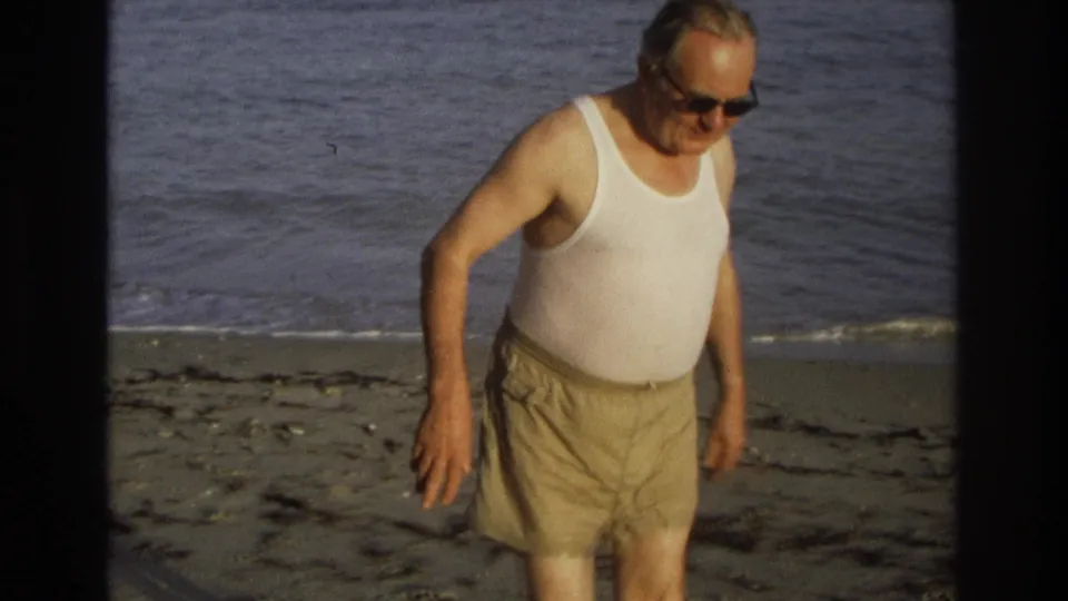 Near the end of the 1968 Ocean City clip, the older man passes closer to camera with ocean and sand behind him.