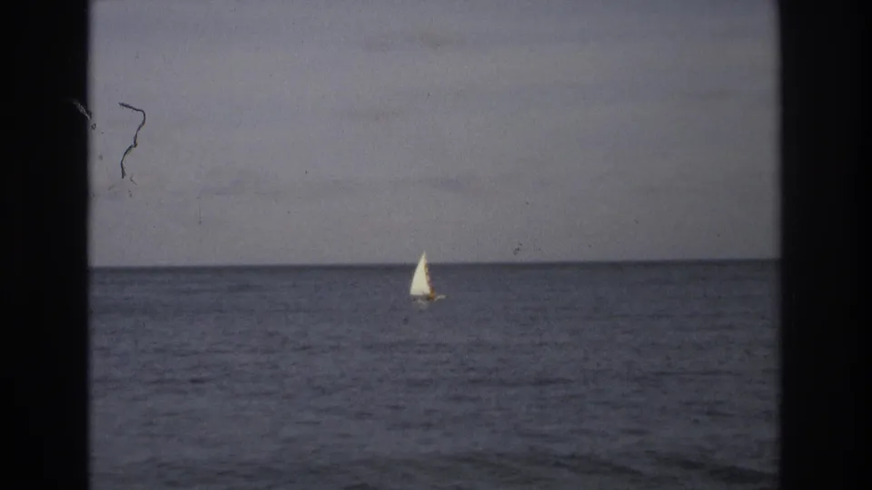 A lone white sailboat moves across calm Atlantic water in 1968 Ocean City home-movie footage, with visible grain and dark scan borders.
