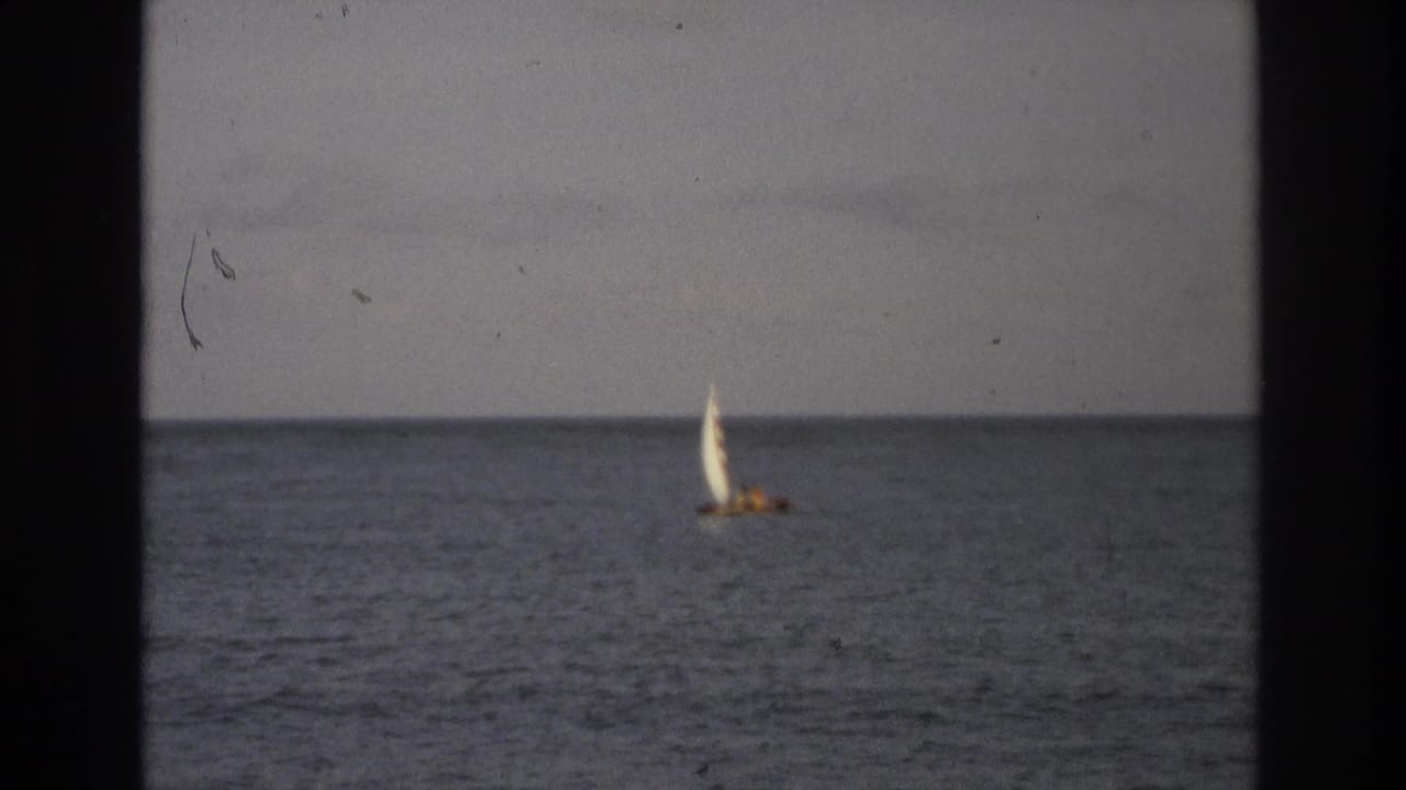 Distant sailboat near the horizon on gray-blue ocean water.