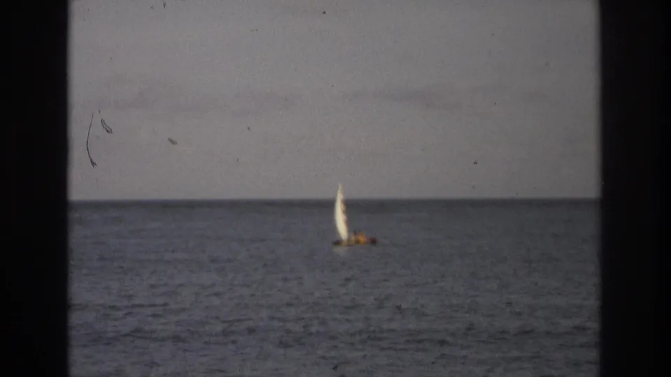 Distant sailboat with a white sail appears near the horizon in 1968 Ocean City, New Jersey home-movie footage.