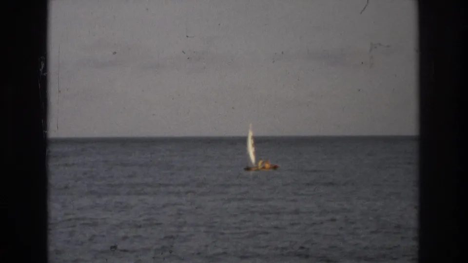 1968 8mm coastal frame from Ocean City, New Jersey showing a small sailboat on calm open water with visible film wear.