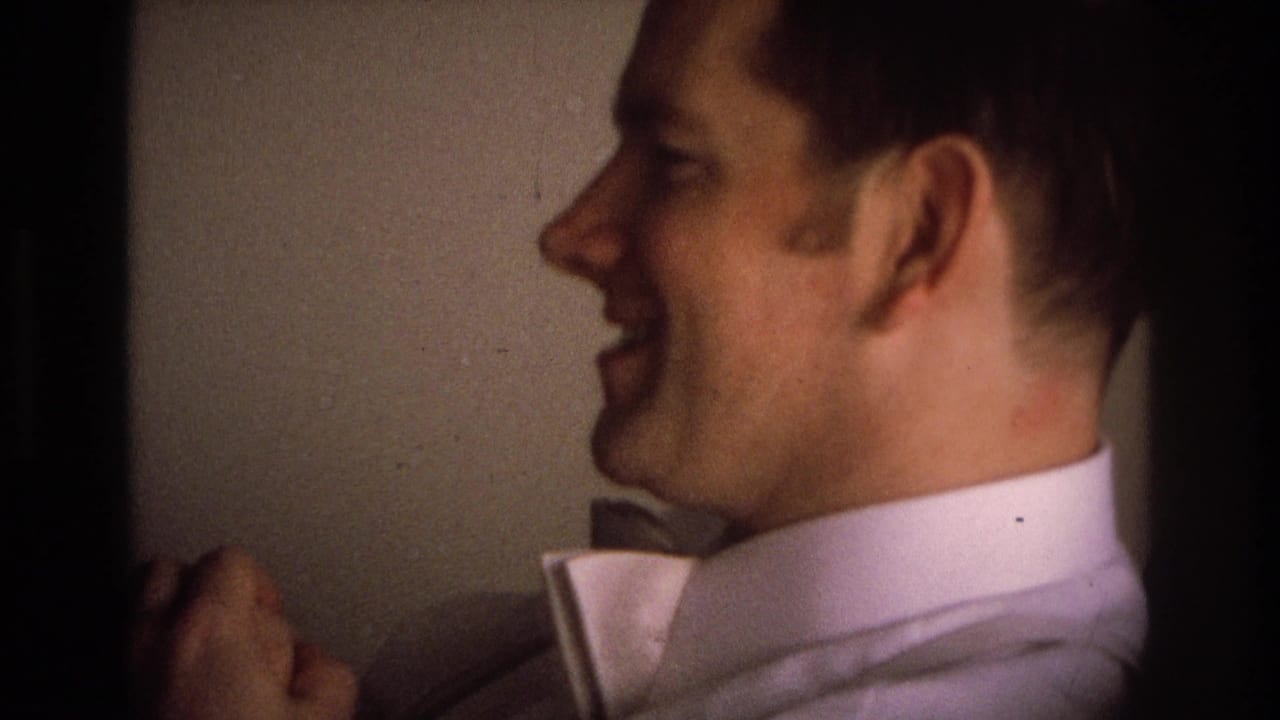 In 1968 Ocean City home-movie footage, a man in profile laughs while wearing a light dress shirt and bow tie in a dim interior.
