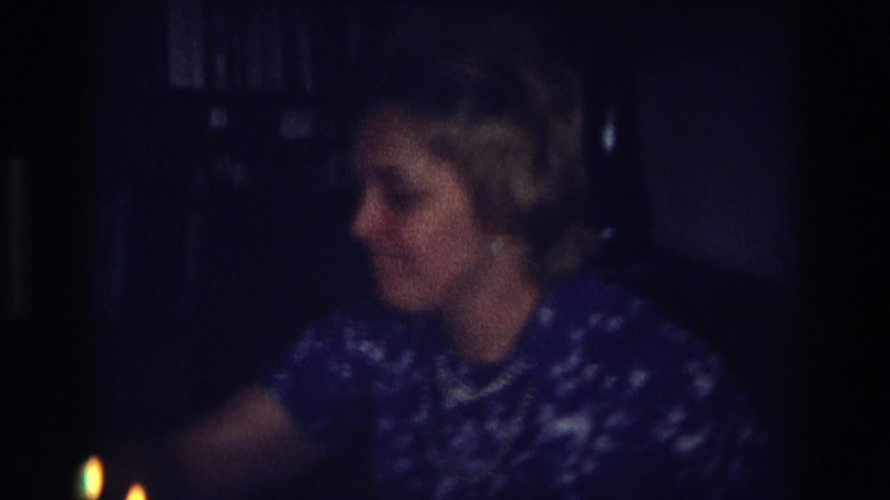 The woman sits turned to the side in a dark 1968 Ocean City interior, with small candle flames visible near the lower edge.
