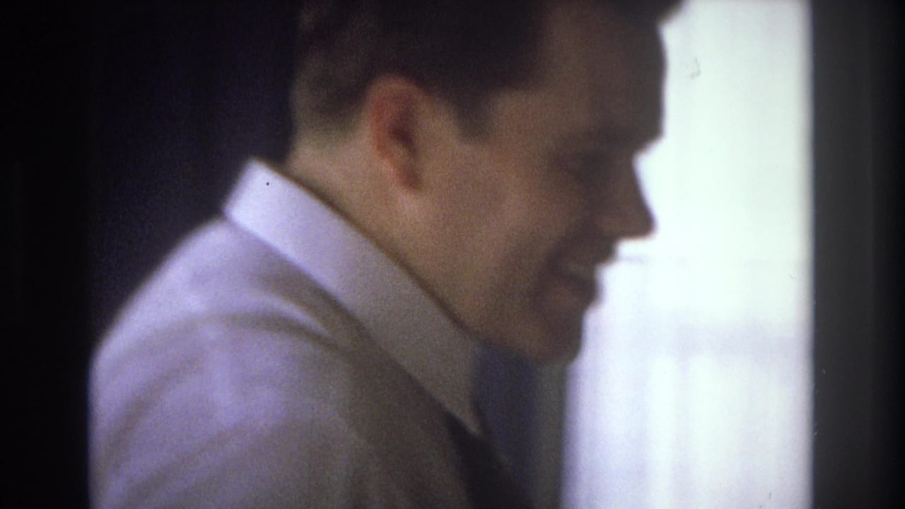 An adult man in a white shirt and dark tie appears in profile in a dim Ocean City, New Jersey interior, with bright light at the edge of frame.