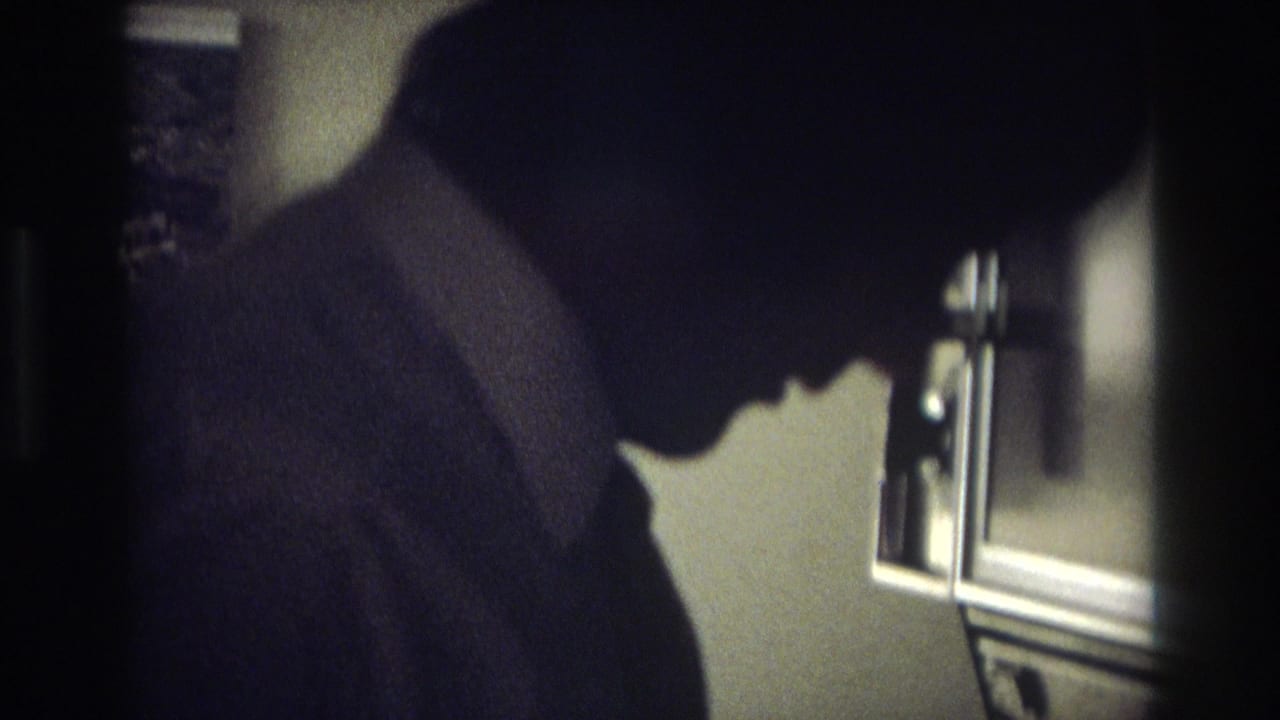 A man in a suit and tie stands in profile near a stove area in a dim Ocean City, New Jersey kitchen scene.