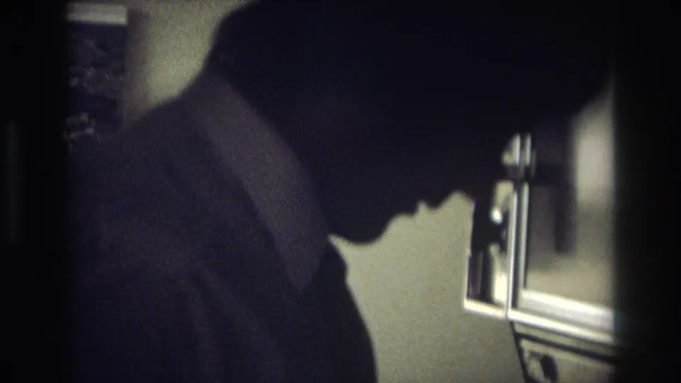 A man in a suit and tie stands in profile near a stove area in a dim Ocean City, New Jersey kitchen scene.