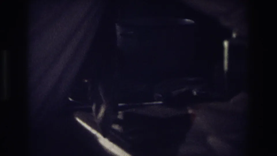 A shadowed profile of the man appears beside the stove, with dark cookware or kitchen objects partly visible in the foreground.
