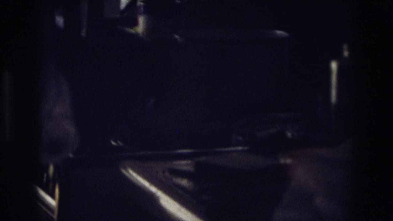 In a dim 1968 Ocean City home kitchen scene, hands appear to prepare bread with a knife on a shadowed counter.