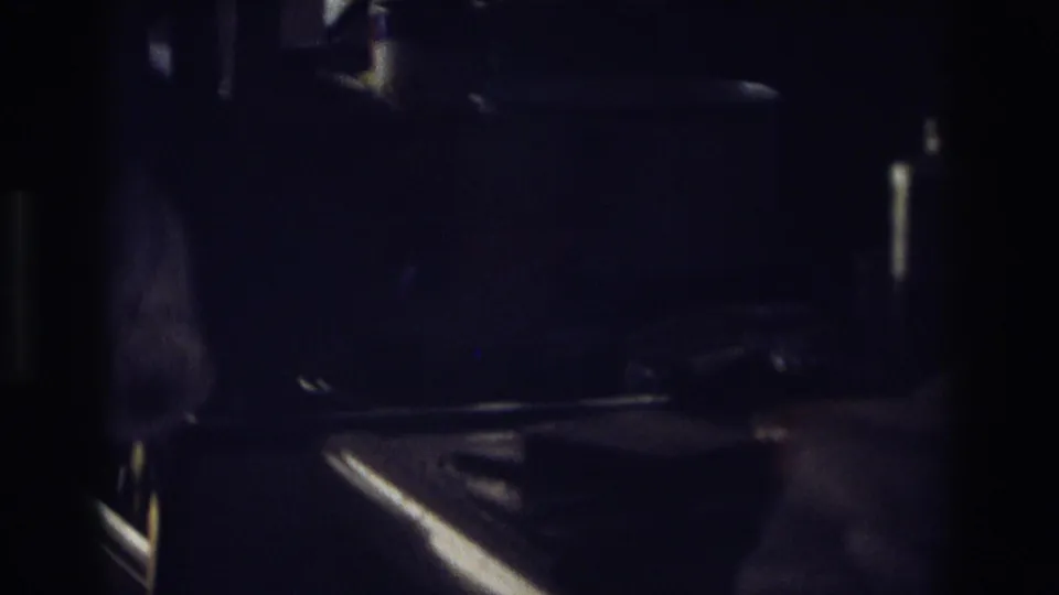In a dim 1968 Ocean City home kitchen scene, hands appear to prepare bread with a knife on a shadowed counter.