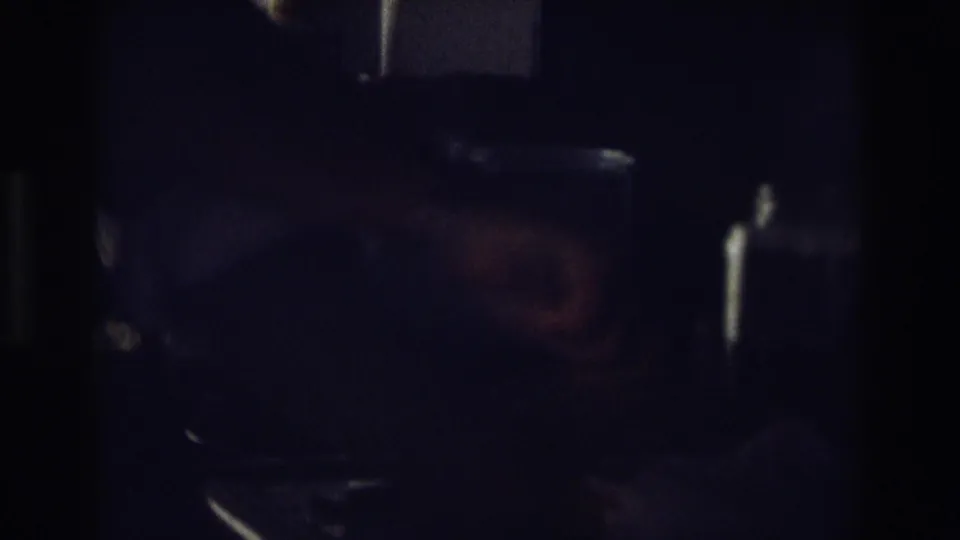 A shadowed 8mm frame shows a partially visible person beside dark kitchen surfaces during the sandwich-making moment.