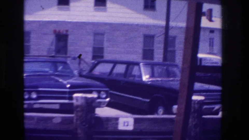 Ocean City, New Jersey frame showing parked 1960s cars beside a wooden dock, with bait shop lettering and home-movie softness.