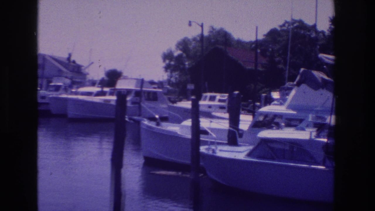 1968 Ocean City, New Jersey home-movie frame of small boats tied near wooden pilings along a quiet marina.
