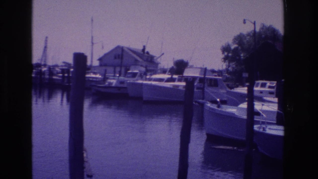 1968 Ocean City bay marina view with docked boats, vertical pilings, masts, and still water in aged 8mm color.