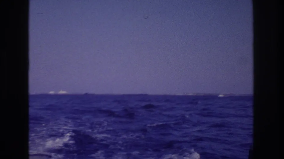 1968 coastal boat-ride frame showing blue water, white wake foam, and a low shoreline in the distance near Ocean City, New Jersey.