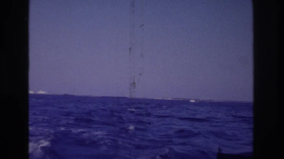 Final boat-ride view over open water toward a distant Ocean City shoreline, with a small part of the boat visible at lower right.
