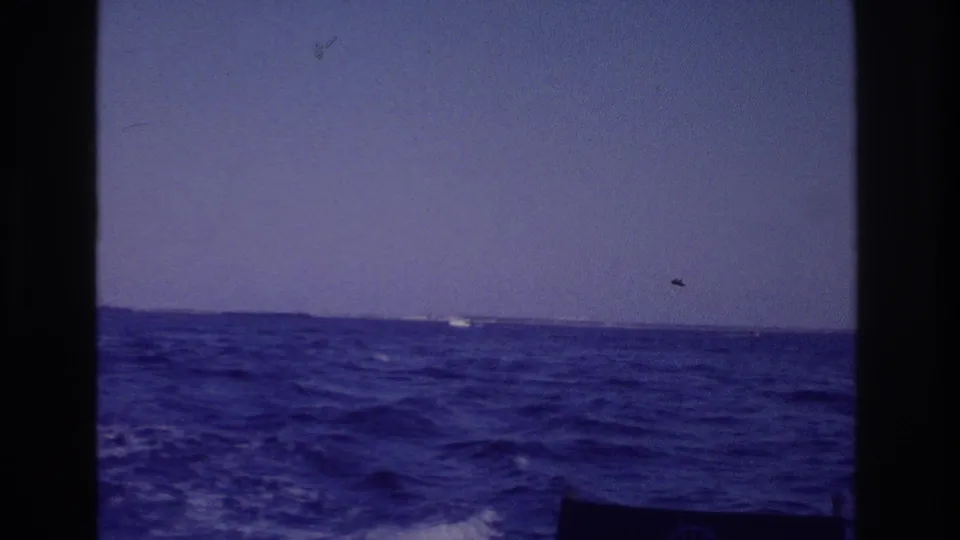 8mm home-movie frame from a boat near Ocean City, New Jersey, showing wake, choppy sea, and a low horizon.