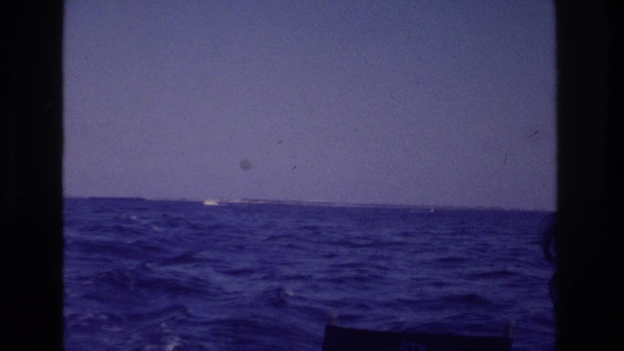 1968 Ocean City home-movie frame showing rough blue ocean, whitecaps, pale sky, and distant shoreline from a moving boat.