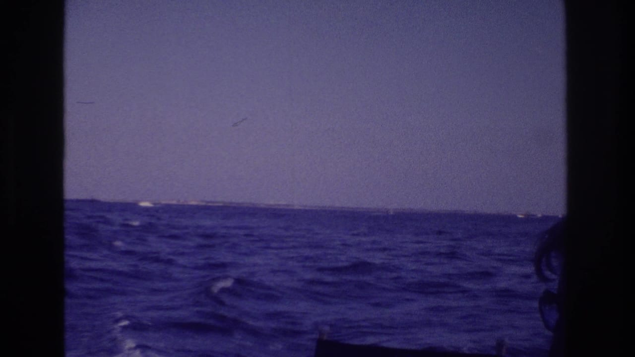 Rolling ocean and low horizon framed by dark vertical boat edges.