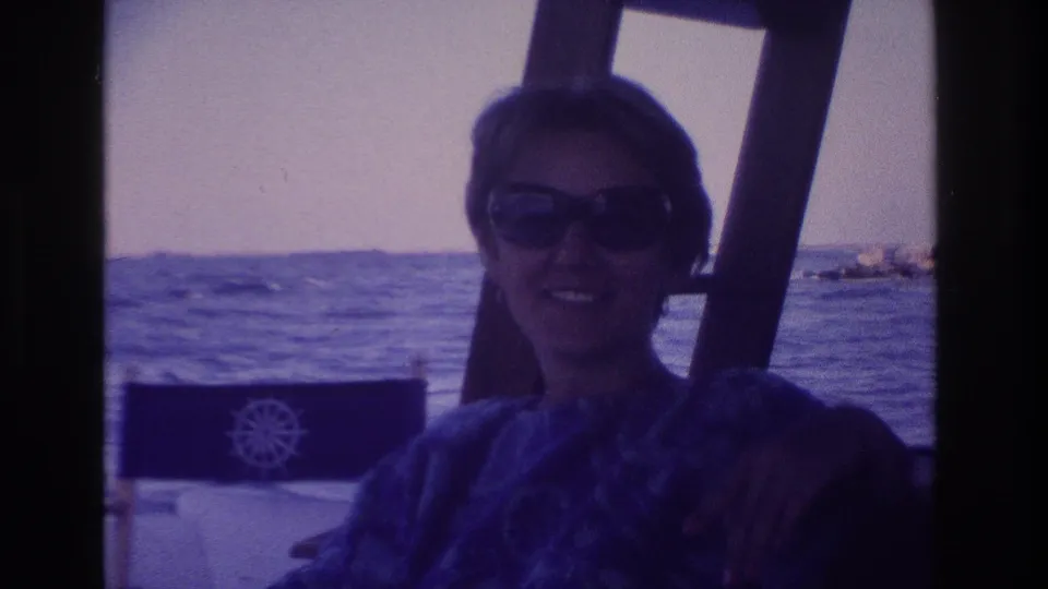 1968 Ocean City, New Jersey home-movie frame of a woman in dark sunglasses seated on a boat near open water.