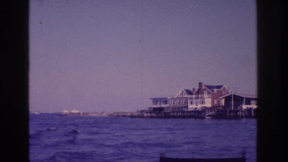 1968 Ocean City home-movie frame showing a waterfront building and low shoreline viewed from a boat on the water.