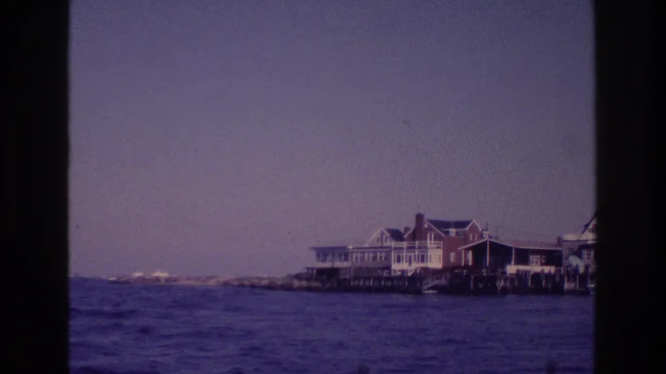 Boat-view frame of Ocean City waterfront buildings, pale sky, and rippled water in purple-blue 8mm color.