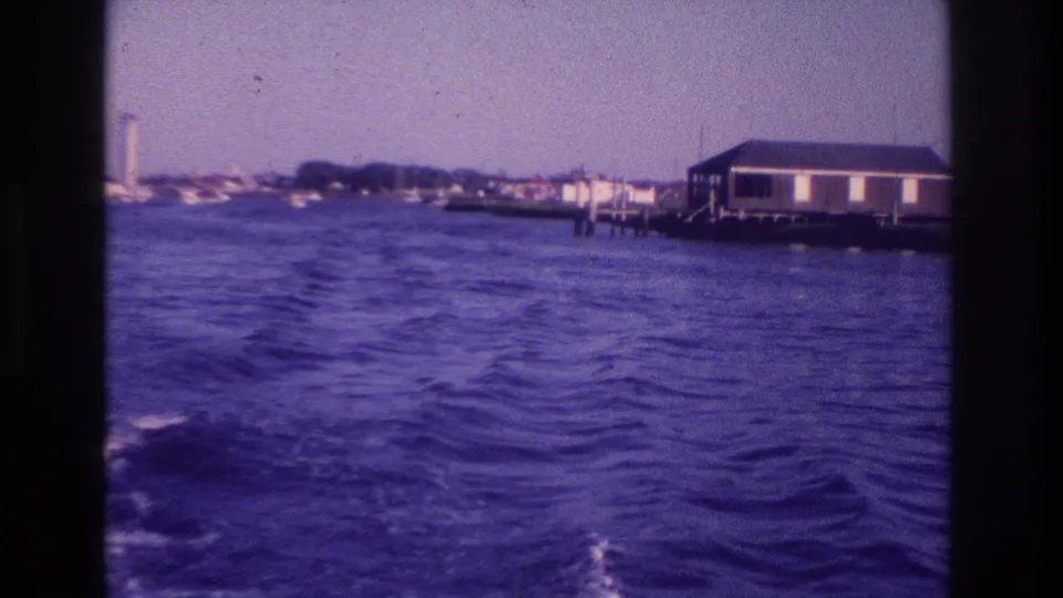 1968 Ocean City, New Jersey 8mm frame showing a waterfront building, dock posts, rippled water, and distant shoreline structures.