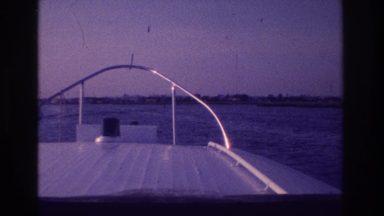 Bow-level 8mm view from a motorboat in Ocean City, New Jersey, with open water, a hazy horizon, and distant shore structures.