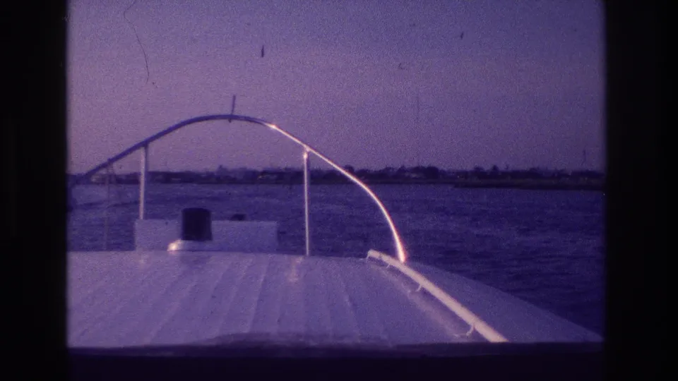 Bow-level 8mm view from a motorboat in Ocean City, New Jersey, with open water, a hazy horizon, and distant shore structures.