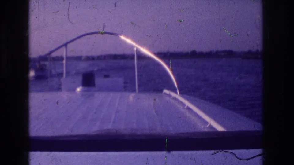 End frame of the 1968 Ocean City boat-view clip, with the bow rail, calm water, distant land, and visible 8mm frame borders.