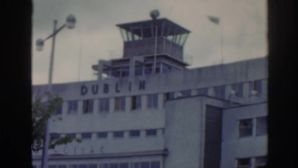 Close view of Dublin Airport control tower and facade lettering, with lamp post and terminal windows below.