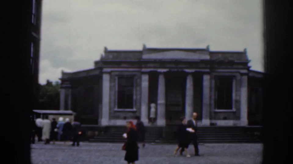 1961 Dublin view across a public courtyard toward a classical stone building as pedestrians move near the steps.