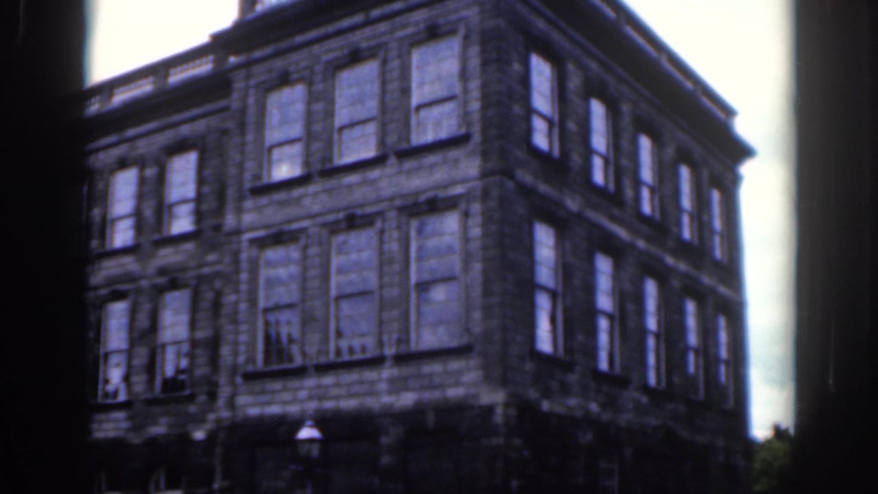 1961 Dublin home-movie view of a large stone urban building with many windows and a dark film-frame border.