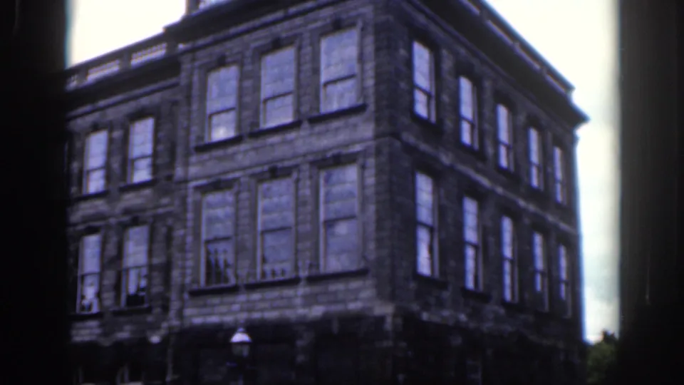 1961 Dublin home-movie view of a large stone urban building with many windows and a dark film-frame border.