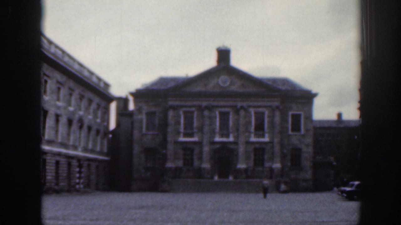 Classical stone building facing a broad nearly empty paved square.