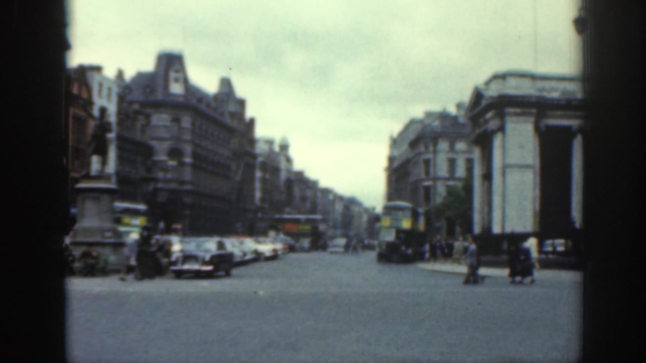 A wider 1961 Dublin street view shows older cars, pedestrians, double-decker buses, and a prominent statue framed by commercial city buildings.