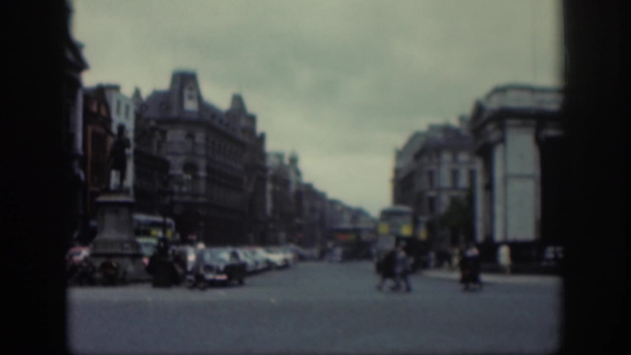 The closing frame shows a broad Dublin street scene with pedestrians crossing, parked cars, double-decker buses, and a statue beside large city buildings.